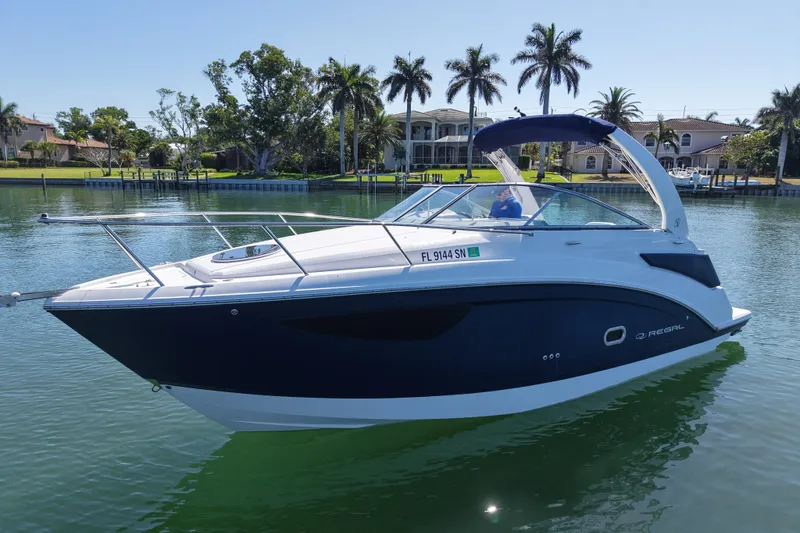Slide: The Image of 2020 Regal 26 XO boat on calm water with palm trees in the background. - 5