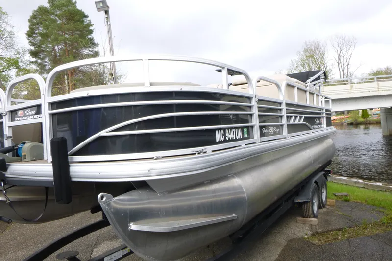 Slide: The Image of 2021 Sun Tracker Fishin' Barge 20 DLX pontoon boat on trailer near water. - 3