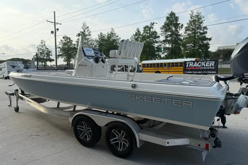 Slide: The Image of 2023 Skeeter SX240 boat on trailer, parked outdoors with trees and vehicles in background. - 6