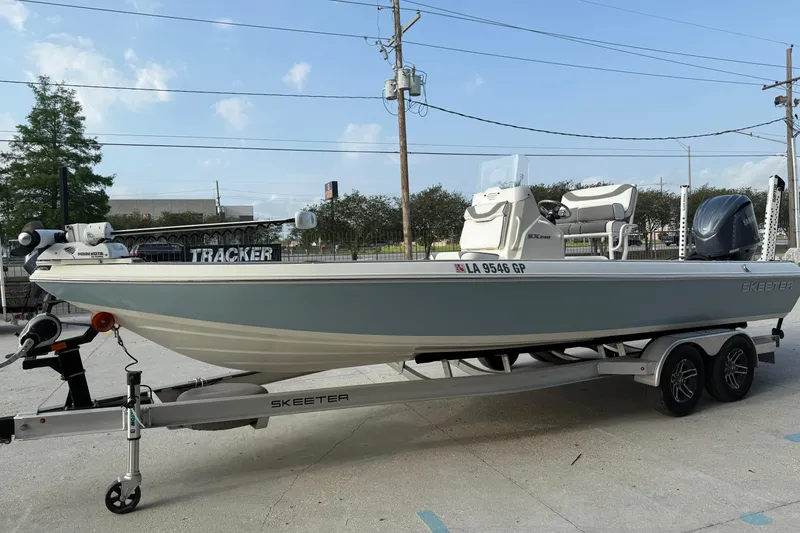 Slide: The Image of 2023 Skeeter SX240 boat on trailer, parked outdoors, showcasing sleek design and modern features. - 7