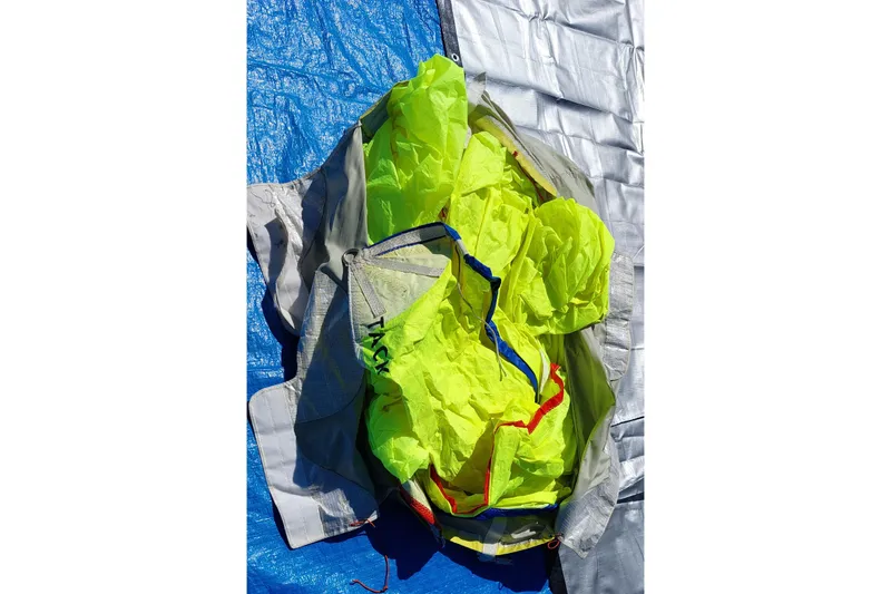 Slide: The Image of Bag containing bright yellow sail, labeled "Mauri Sails," on concrete floor. - 21