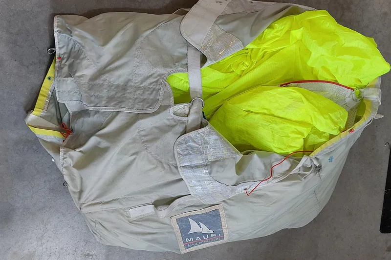 Slide: The Image of Bag labeled "Mauri Sails" on blue tarp, containing bright yellow fabric. - 22