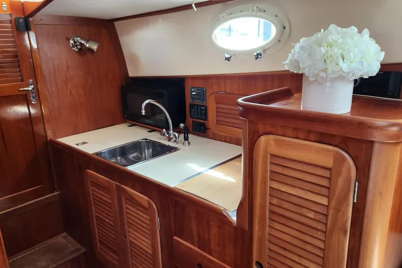 Slide: The Image of 2003 Hinckley Picnic Boat EP interior with wooden cabinetry and compact kitchen area. - 10