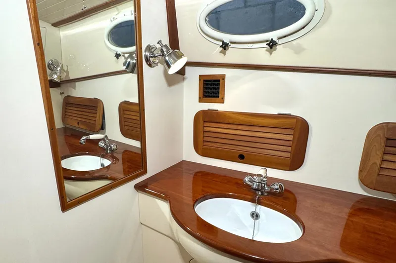 Slide: The Image of 2003 Hinckley Picnic Boat EP bathroom with wooden accents and oval mirror. - 14
