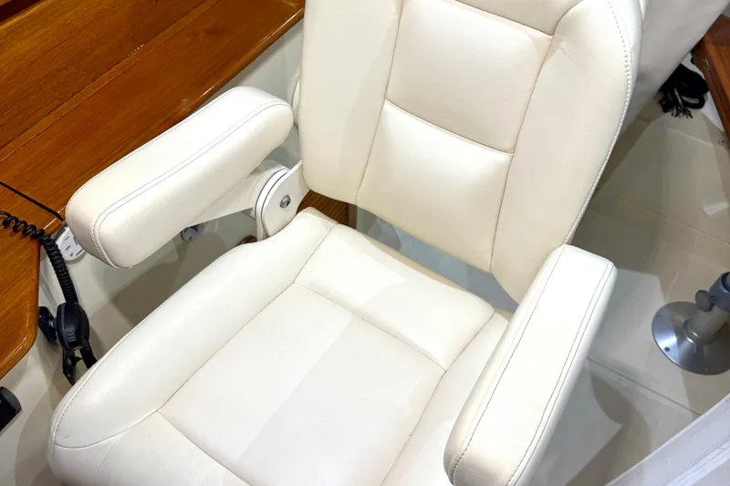 Slide: The Image of White captain's chair on 2003 Hinckley Picnic Boat EP, featuring wooden accents and armrests. - 9