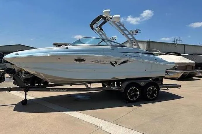 The Image of 2024 Crownline Eclipse E235 SURF boat on trailer, parked outdoors under clear sky. - 1
