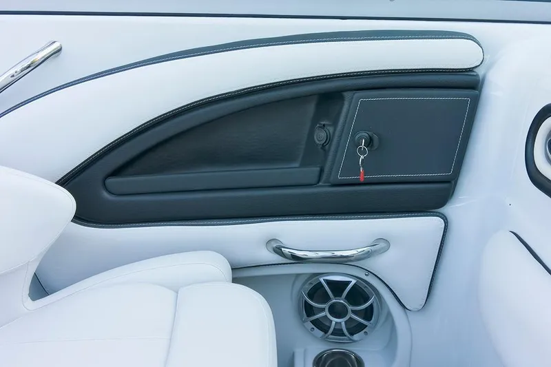 Slide: The Image of 2024 Crownline Eclipse E235 SURF interior with sleek white and black design, featuring a speaker and storage compartment. - 8