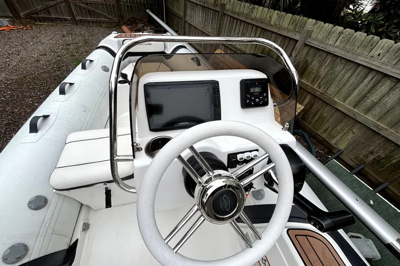Slide: The Image of 2022 Walker Bay Venture 14 boat cockpit with steering wheel and navigation system. - 5
