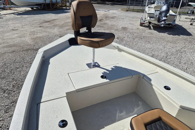 Slide: The Image of 2026 Xpress H20B Bay boat with tan seating, parked on gravel. - 13
