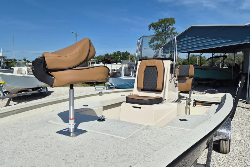 Slide: The Image of 2026 Xpress H20B Bay boat with tan seating, parked outdoors under a blue sky. - 3