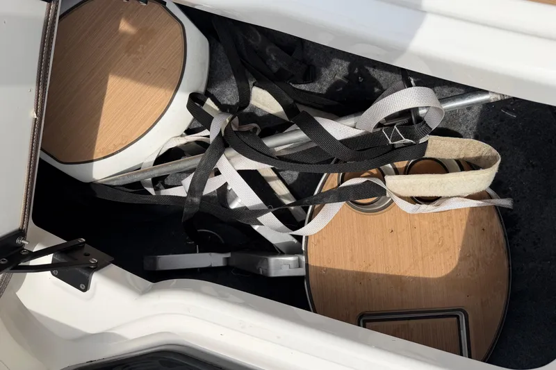 Slide: The Image of Storage compartment of 2022 Yamaha Boats 252SE with straps and wooden panels. - 13