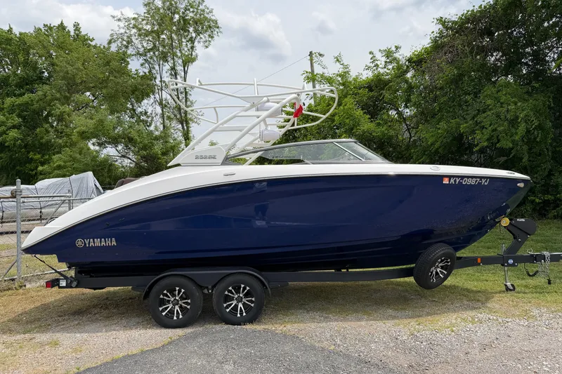 Slide: The Image of 2022 Yamaha Boats 252SE on trailer, parked outdoors with lush greenery background. - 15