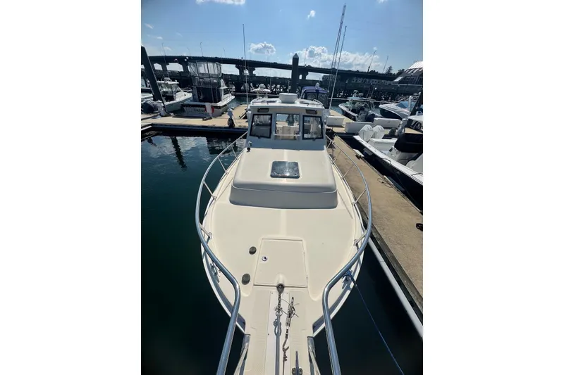 Slide: The Image of 2004 Mainship Pilot 30-II docked at marina, showcasing spacious deck and sleek design. - 14