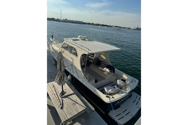 Slide: The Image of 2004 Mainship Pilot 30-II docked by the water, featuring spacious seating and sleek design. - 15