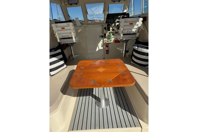 Slide: The Image of 2004 Mainship Pilot 30-II interior with wooden table and striped cushions. - 20