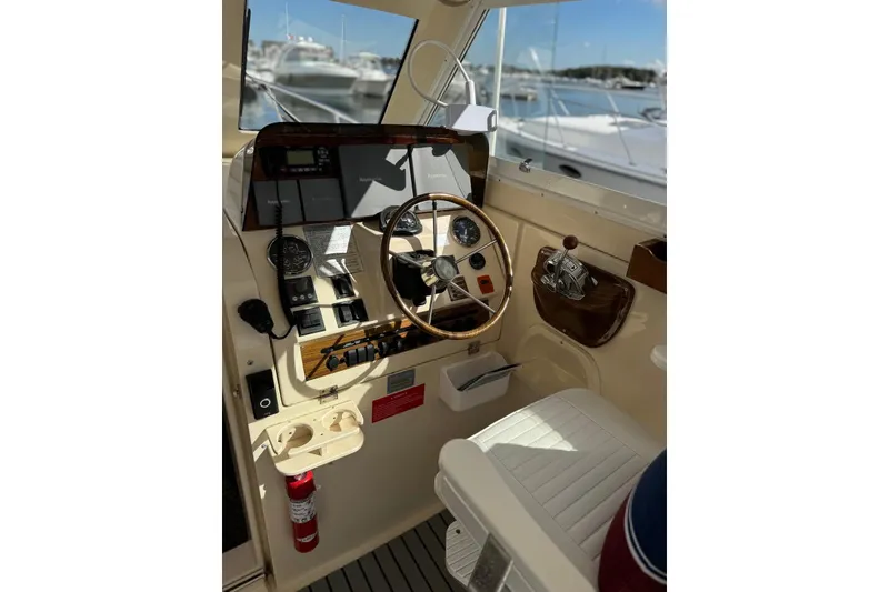 Slide: The Image of 2004 Mainship Pilot 30-II helm with steering wheel, gauges, and controls in a marina setting. - 22
