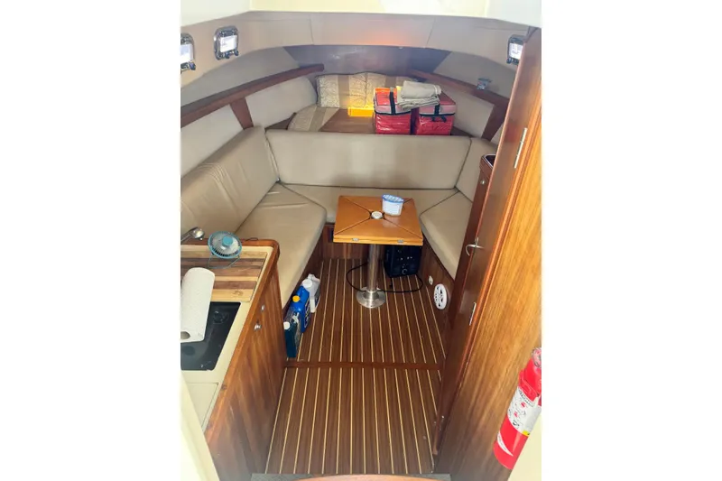 Slide: The Image of 2004 Mainship Pilot 30-II cabin interior with seating, table, and kitchenette. - 24