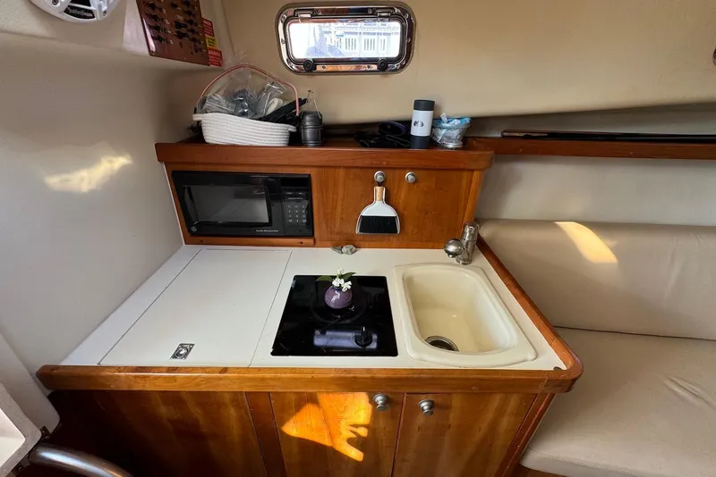 Slide: The Image of 2004 Mainship Pilot 30-II boat galley with sink, stove, and microwave. - 26