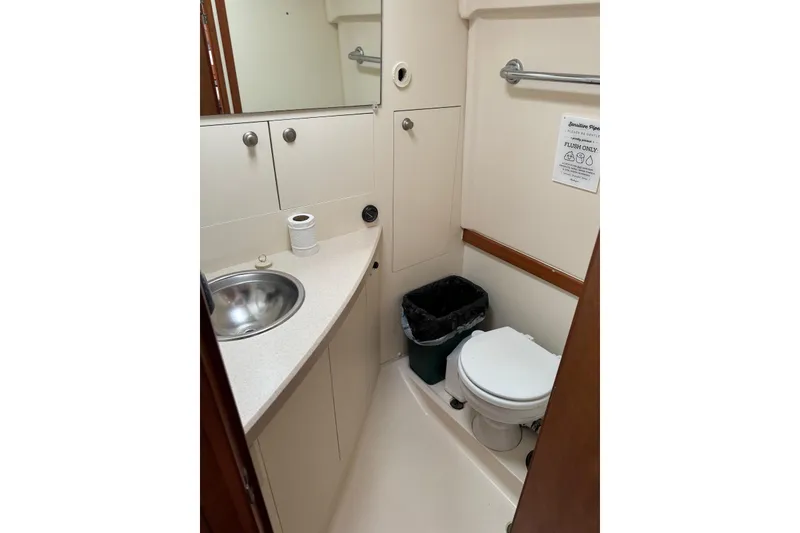 Slide: The Image of 2004 Mainship Pilot 30-II boat bathroom with sink, toilet, and storage cabinets. - 28