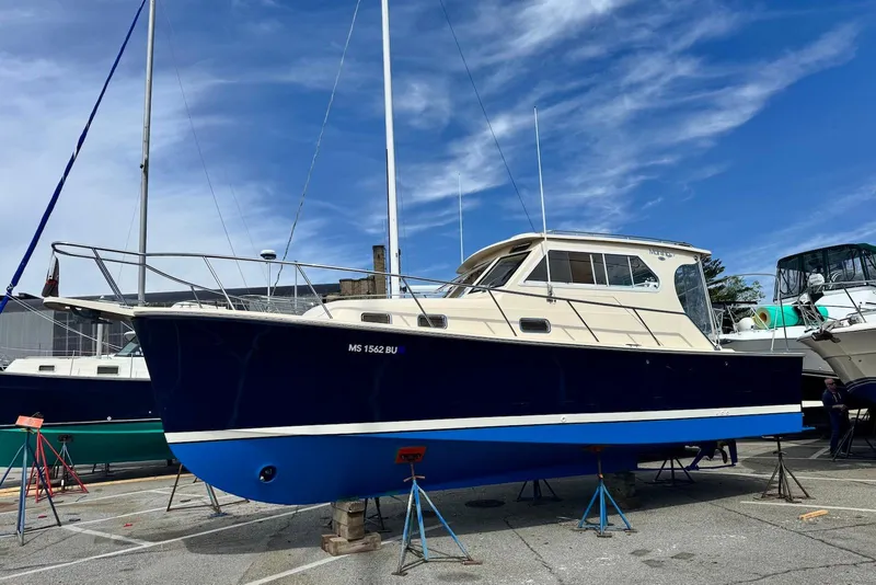 Slide: The Image of 2004 Mainship Pilot 30-II boat on stands, blue hull, clear sky background. - 30