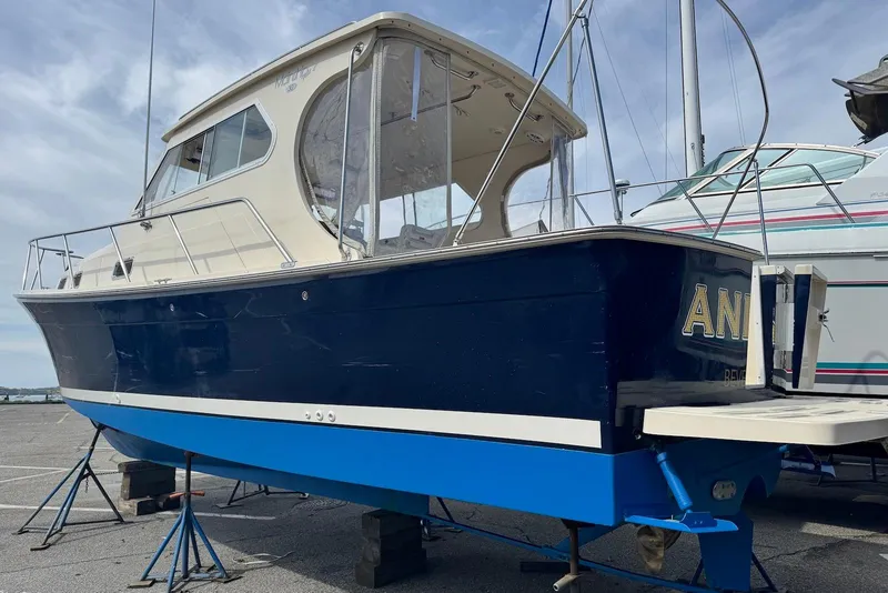 Slide: The Image of 2004 Mainship Pilot 30-II boat on stands, blue hull, docked outdoors. - 31