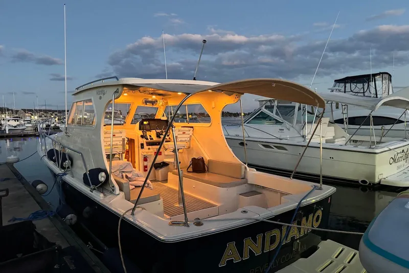 Slide: The Image of 2004 Mainship Pilot 30-II boat docked at marina during sunset, interior lights on. - 6