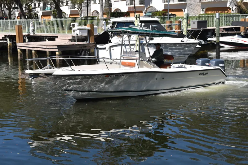 The Image of 2001 Pursuit 2470 Center Console boat cruising in a marina with docked boats. - 0