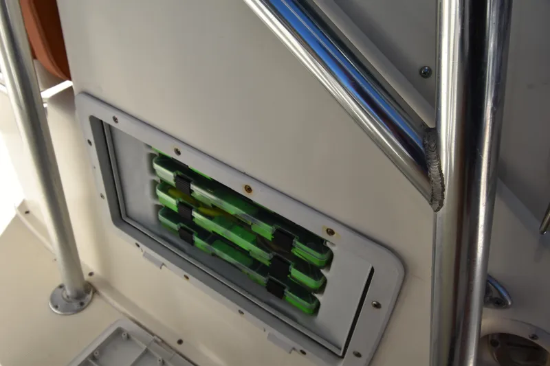 Slide: The Image of Storage compartment on a 2001 Pursuit 2470 Center Console boat, featuring green tackle boxes. - 11