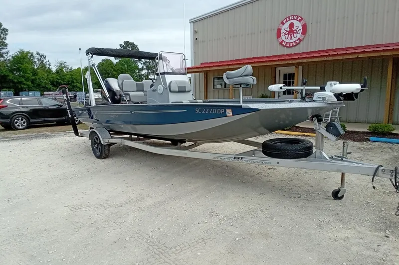 Slide: The Image of 2021 Xpress H20B Bay boat on trailer outside a building with red roof. - 3