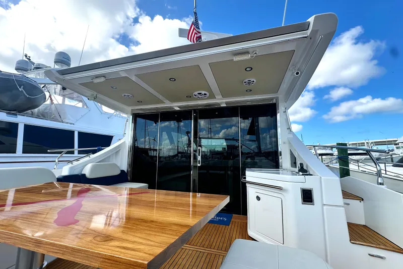 Slide: The Image of 2015 Azimut 55S yacht deck with wooden table, glass doors, and marina view. - 11