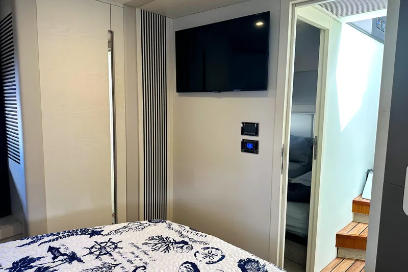 Slide: The Image of Interior of 2015 Azimut 55S yacht bedroom with TV, nautical bedding, and wooden stairs. - 32