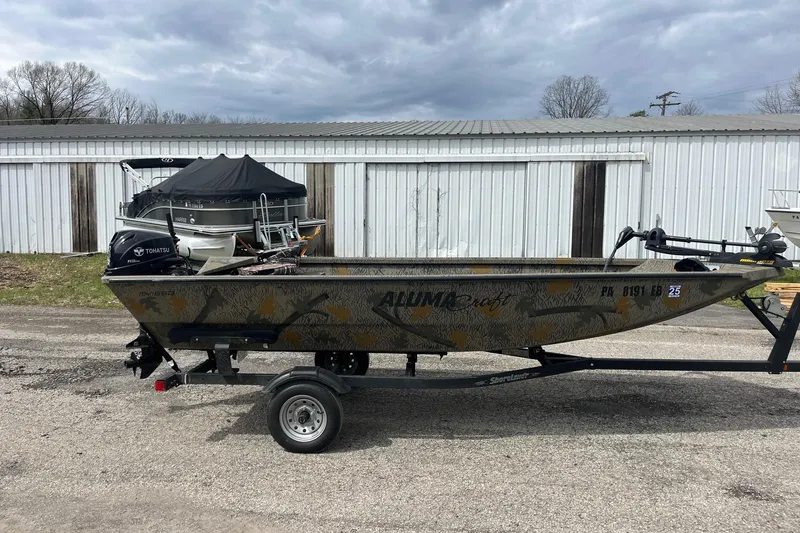 Slide: The Image of 2022 Alumacraft 1650 All Weld MV Tiller boat on trailer, parked outdoors. - 5