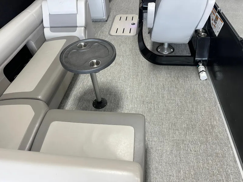 Slide: The Image of Interior of 2024 Premier 230 Sunsation TRITOON with gray seating and table. - 24