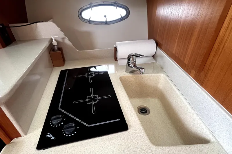 Slide: The Image of 1999 Tiara Yachts 3500 Open galley with stove, sink, and porthole window. - 9