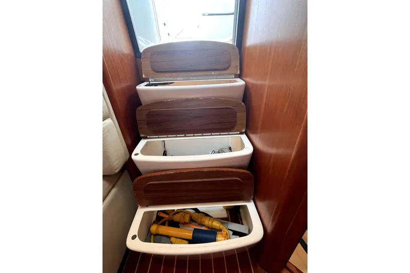 Slide: The Image of Storage compartments inside a 1999 Tiara Yachts 3500 Open, featuring wooden lids and nautical equipment. - 11