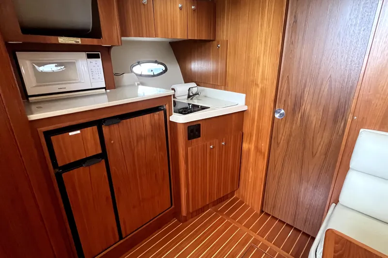 Slide: The Image of 1999 Tiara Yachts 3500 Open interior kitchen with microwave, sink, and wooden cabinetry. - 8