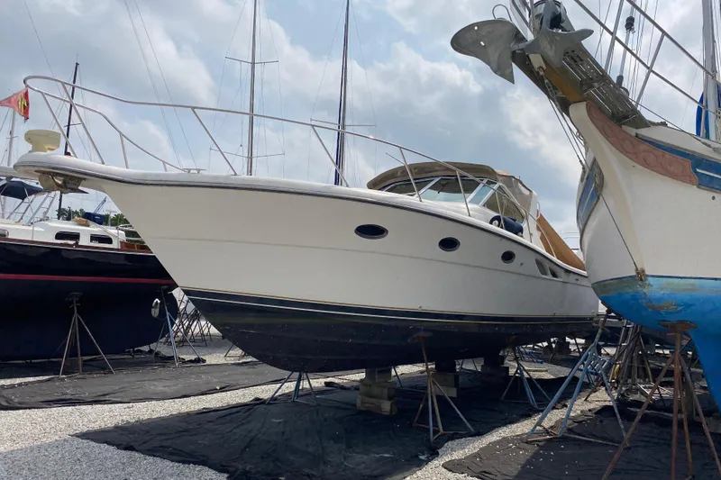 Slide: The Image of 1999 Tiara Yachts 3500 Open on dry dock, surrounded by other boats under a cloudy sky. - 1