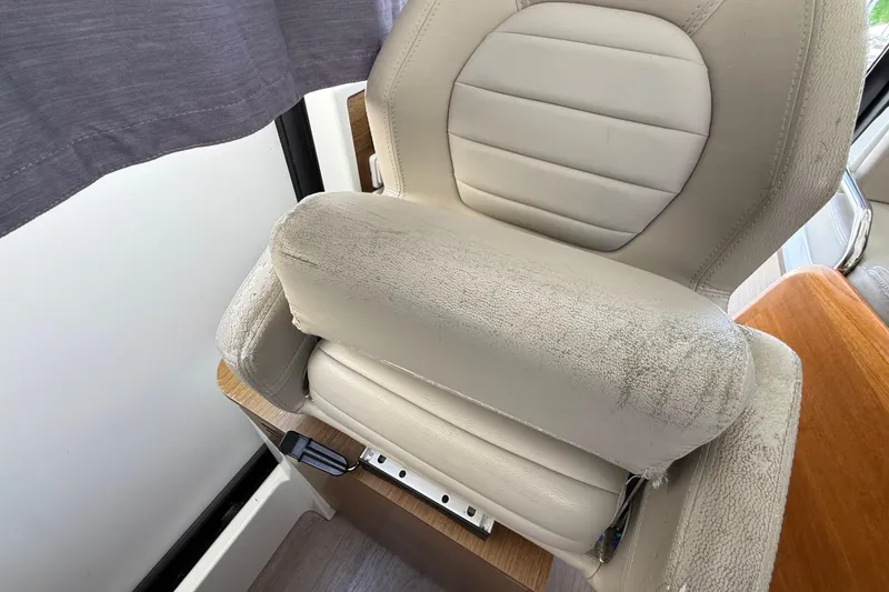 Slide: The Image of Captain's seat in a 2021 Jeanneau NC 895 boat, featuring plush beige upholstery. - 25