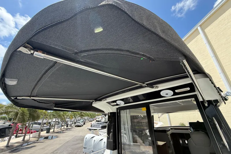 Slide: The Image of 2021 Jeanneau NC 895 boat canopy with stainless steel supports, docked under a clear blue sky. - 46