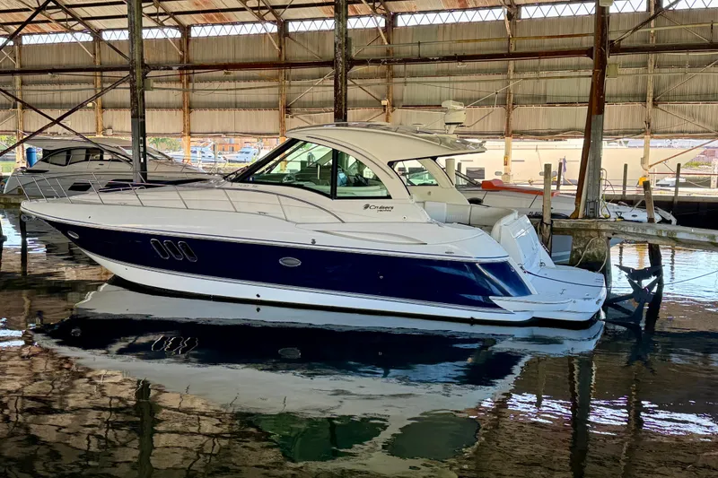 The Image of 2012 Cruisers Yachts 430 Sports Coupe docked in a marina, reflecting on calm water. - 0