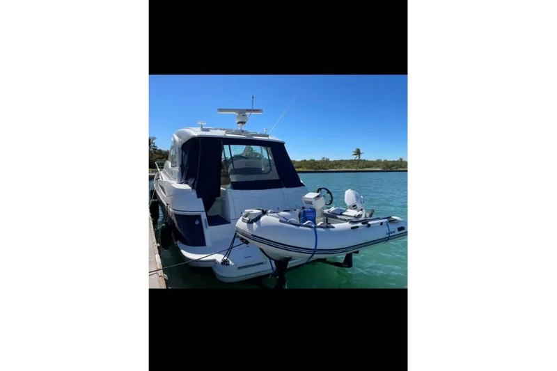 Slide: The Image of 2012 Cruisers Yachts 430 Sports Coupe docked with inflatable boat on water. - 29