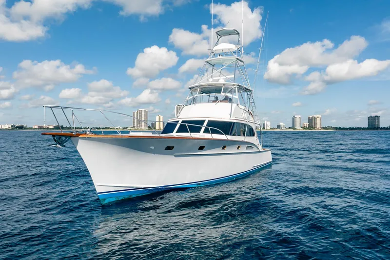 Slide: The Image of 1983 Rybovich 55 Convertible yacht on open water with city skyline background. - 112