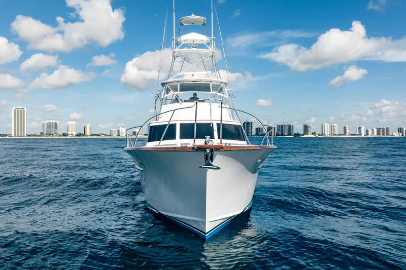 Slide: The Image of 1983 Rybovich 55 Convertible yacht on open water with city skyline backdrop. - 113