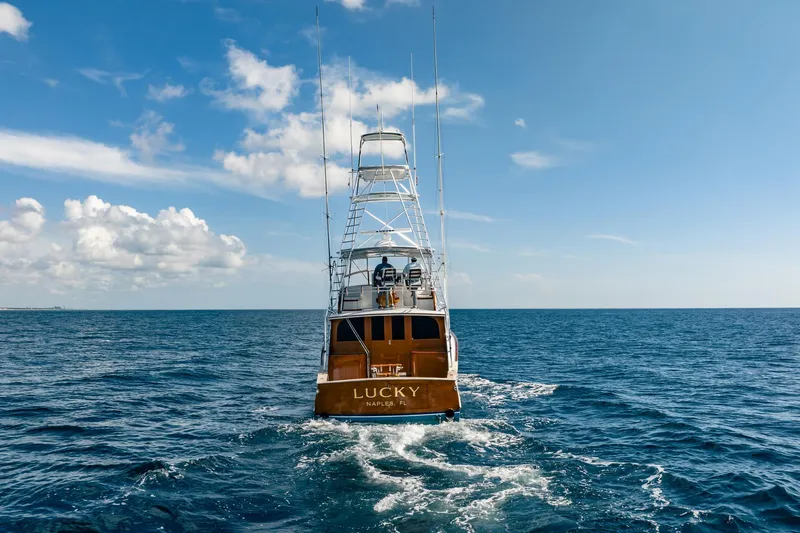 Slide: The Image of 1983 Rybovich 55 Convertible yacht "Lucky" cruising on open ocean under blue sky. - 115