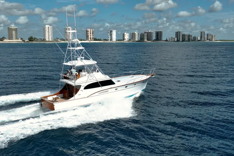 Slide: The Image of 1983 Rybovich 55 Convertible yacht cruising on ocean with city skyline in background. - 123