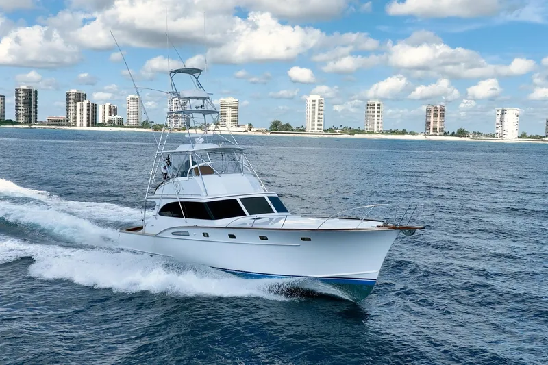 Slide: The Image of 1983 Rybovich 55 Convertible yacht cruising near city skyline. - 2