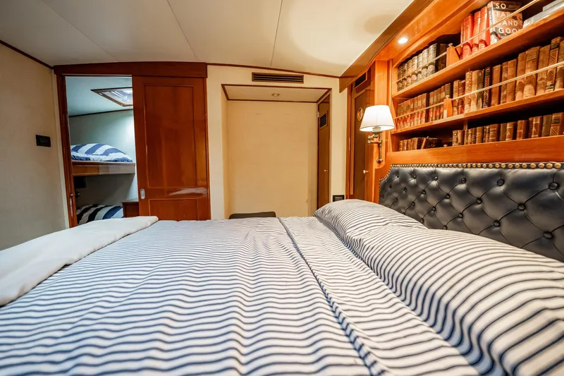 Slide: The Image of Luxurious cabin interior of 1983 Rybovich 55 Convertible yacht with striped bedding and bookshelf. - 44
