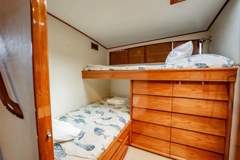 Slide: The Image of 1983 Rybovich 55 Convertible cabin with wooden bunk beds and nautical-themed bedding. - 46