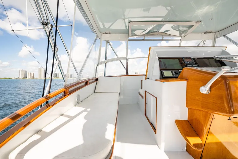 Slide: The Image of 1983 Rybovich 55 Convertible yacht interior with helm, overlooking ocean and city skyline. - 63