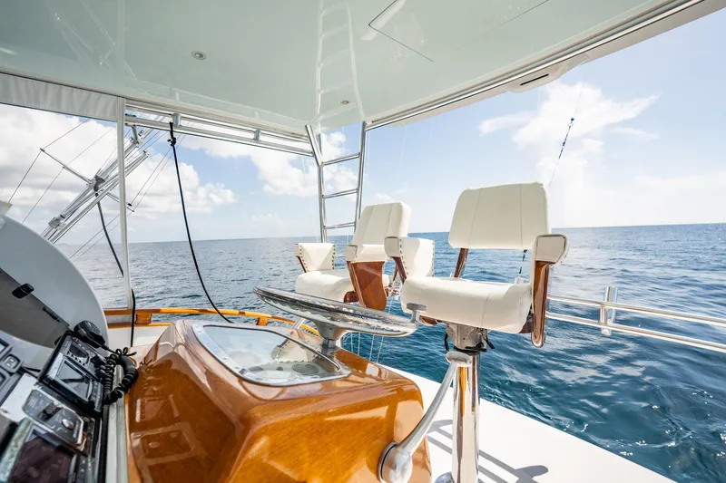 Slide: The Image of 1983 Rybovich 55 Convertible yacht interior with ocean view, featuring white chairs and wooden accents. - 69